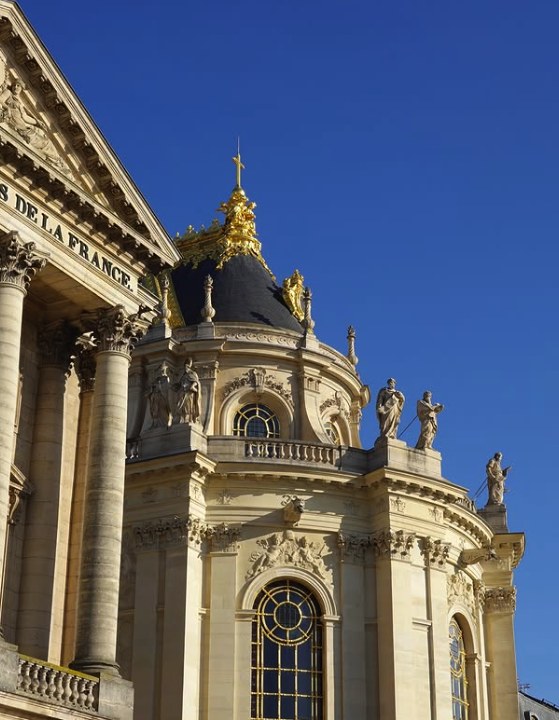 The gilded apex of the Royal Chapel roof at Versailles, beside the pediment carrying the dedication to all the glories of France